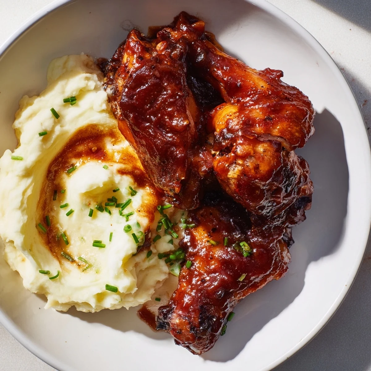 Golden-brown Honey BBQ Chicken Thighs glistening beside a fluffy pile of garlic mashed potatoes.