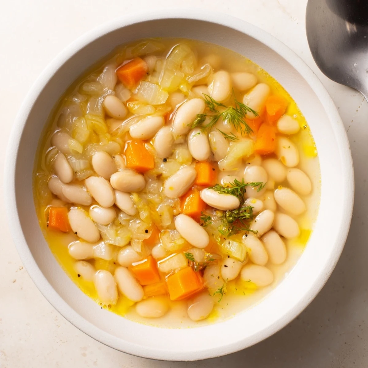 Enjoy a steaming bowl of homemade simple white bean and fennel soup, perfect for a cozy, flavorful dinner.