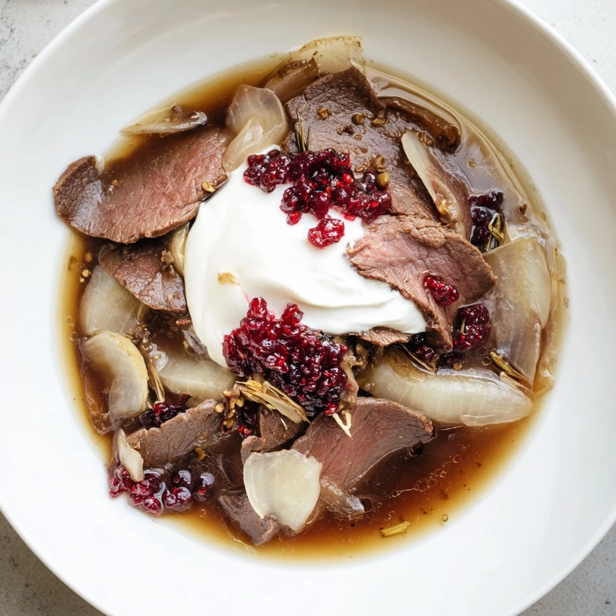 Sizzling Finnish Reindeer Stew, served in a rustic bowl beside creamy mashed potatoes and lingonberries.