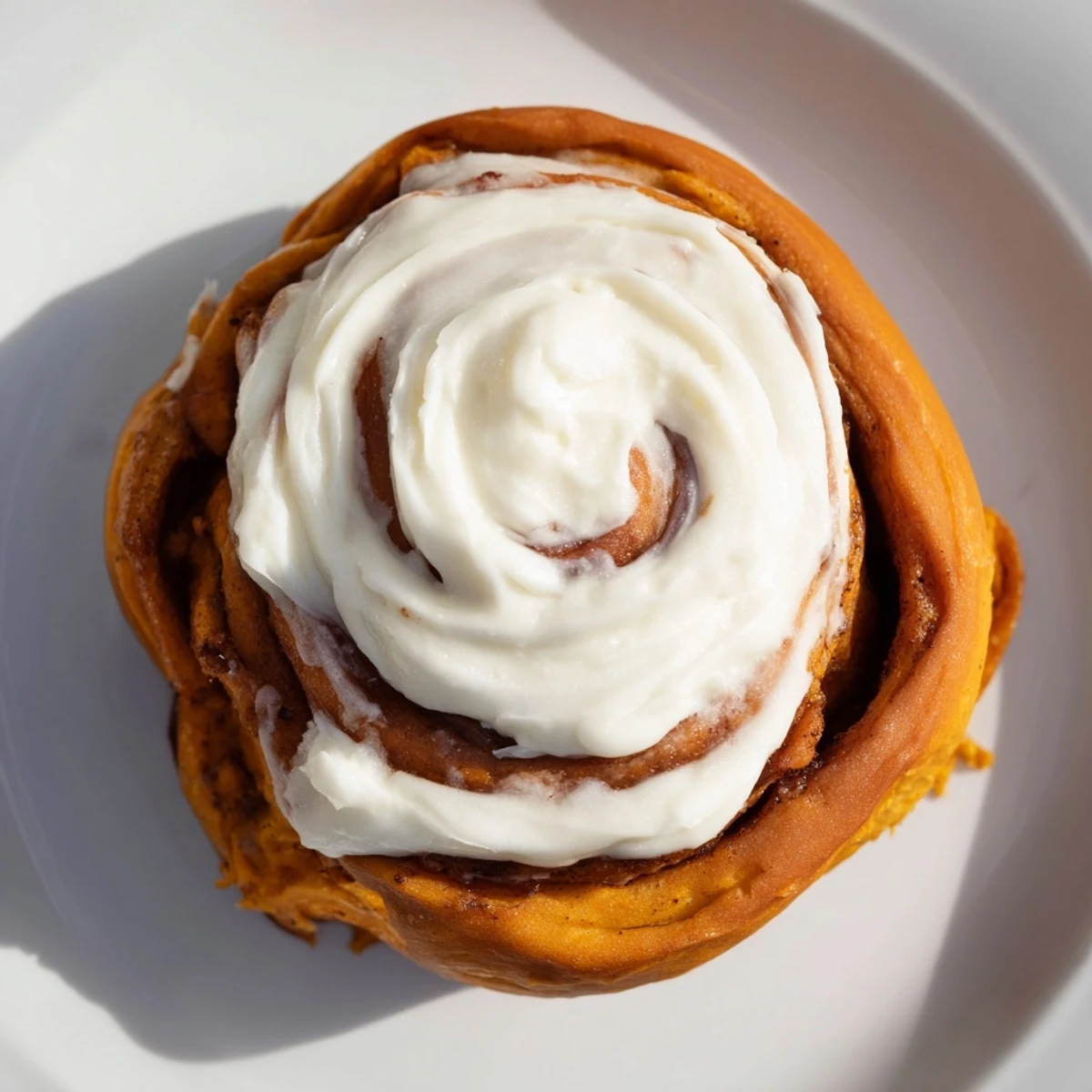 Warm, golden Pumpkin Cinnamon Rolls, drizzled with sweet cream cheese frosting – a delicious breakfast.