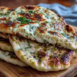 Warm The Best Easy Garlic Naan Bread brushed with melted garlic butter, flecked with herbs, ideal for scooping up creamy Indian dal.