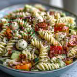 A refreshing summer pasta salad featuring crisp vegetables, creamy mozzarella, and tangy Italian dressing, perfect for picnics or light meals.