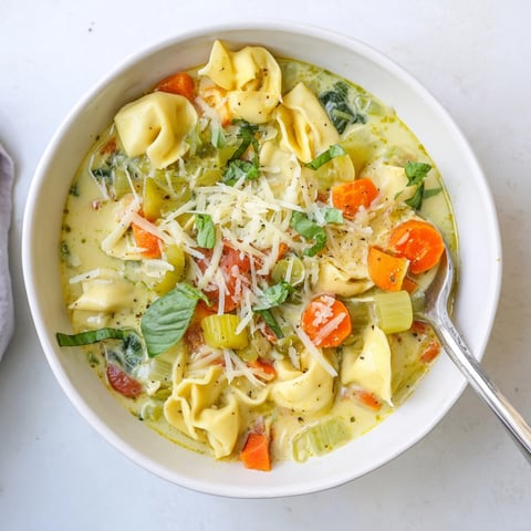 Creamy bowl of Healthier Slow Cooker Creamy Tortellini Soup, ready for garnish with fresh parsley.