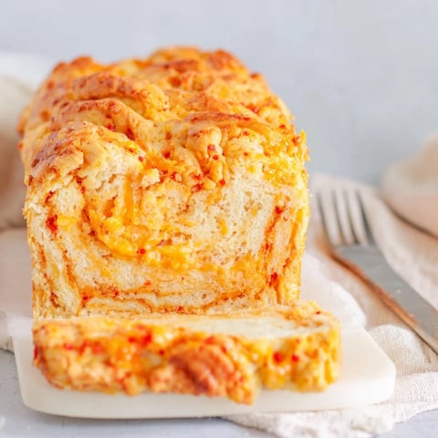 Flamin Hot Cheddar Cinnamon Sugar Biscuit Muffin Loaf drizzled with melted butter, bursting with flavor.  