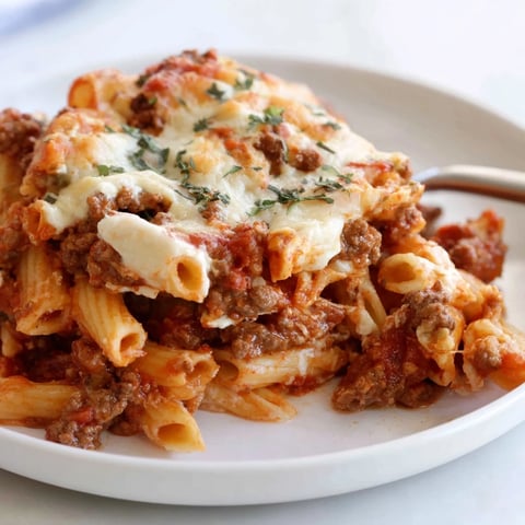A bubbling dish of baked ziti with meat sauce topped with gooey melted cheese.  