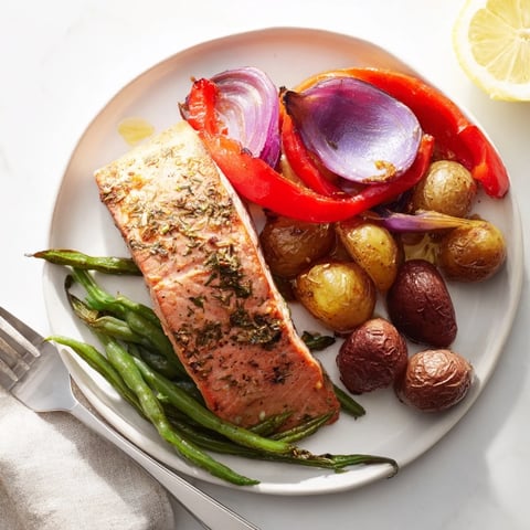 Golden-brown Lemon Herb Salmon & Potato sheet pan, ready to serve with fragrant herbs and lemon wedges.