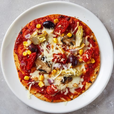 Golden-crusted tortilla pizza with vibrant toppings of olives and roasted red peppers, ready to eat.