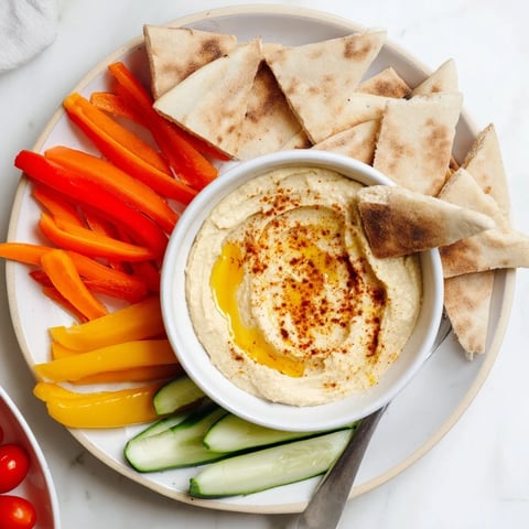 Creamy DIY Hummus with warm pita bread and colorful veggie sticks, perfect for dipping.