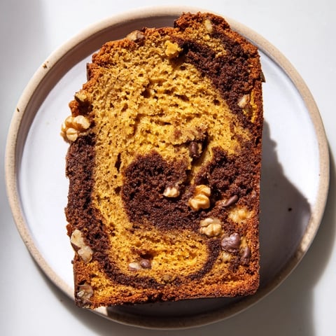 Warm, spiced pumpkin bread loaf, golden-brown and ready to serve with a dusting of powdered sugar.