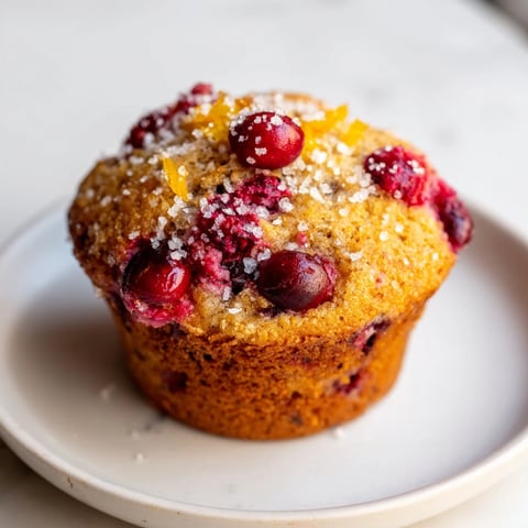 Golden brown Quick Festive Cranberry Orange Muffins, offering a delightful blend of sweet and tart flavors.