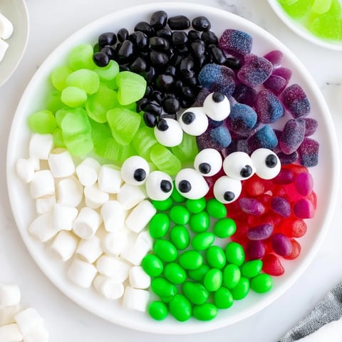 A vibrant Poison Apple Candy Platter, packed with green apple gummies and spooky eyeball candies.