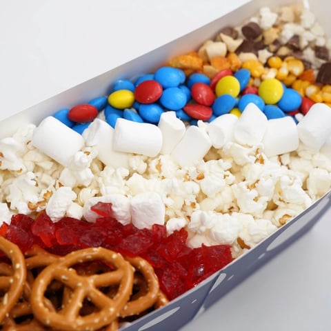 Movie night popcorn boxes filled with classic popcorn and diverse sweet and savory snacks.
