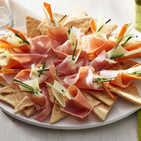 Beautifully arranged The Paper Crane appetizer, featuring crisp crackers and folded cured meats, perfect for entertaining.