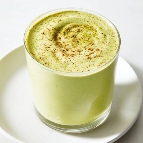 Smooth, green Matcha Eggnog Collagen Breakfast Smoothie swirled in a glass, ready to enjoy.