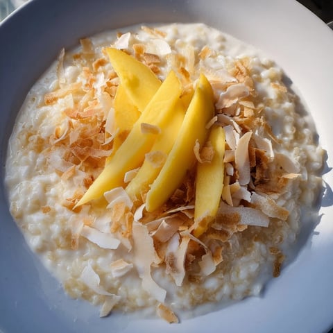 Creamy Toasted Coconut Rice Pudding topped with golden toasted coconut and fresh mango slices.