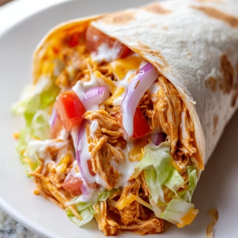 Golden-brown Buffalo Chicken Wrap, layered with veggies, cheese, and a creamy ranch drizzle.
