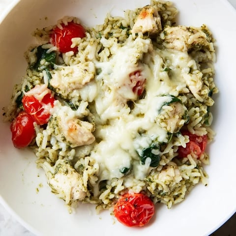 Chicken Pesto Rice Bake bubbling in a casserole dish, topped with melted cheese and fresh basil.