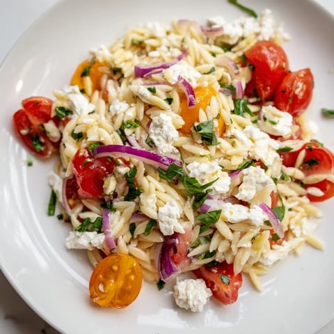 Vibrant Tomato Feta Orzo pasta salad, tossed with fresh herbs in a simple, zesty dressing.