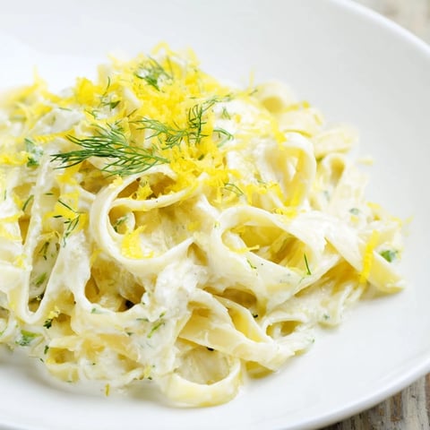 Golden Creamy Dill Pasta topped with fresh dill and Parmesan cheese, ready to eat.