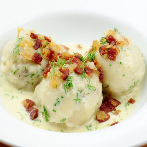 Golden, oval-shaped Cepelinai dumplings, ready to be enjoyed with flavorful bacon and sour cream sauce.