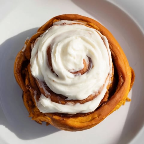Warm, golden Pumpkin Cinnamon Rolls, drizzled with sweet cream cheese frosting – a delicious breakfast.