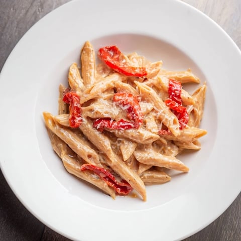 Creamy Cajun pasta with roasted red bell peppers and fresh parsley, served warm on a plate with a fork.