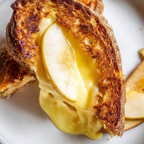 Golden-brown sourdough grilled cheese with melted smoked Gouda and crisp apple slices, served on a rustic plate.
