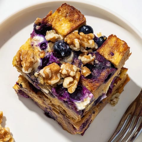 Scoops of Protein Blueberry French Toast Bake, a nourishing brunch topped with pecans.