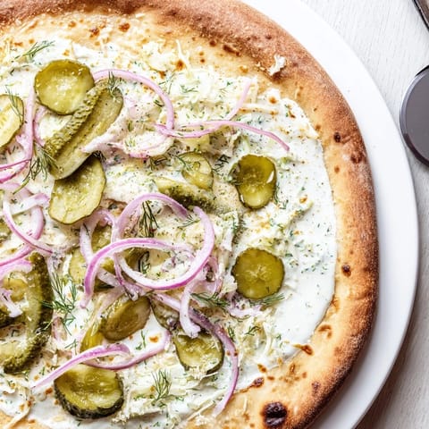Deliciously unique Pickle Pizza topped with melted mozzarella and fresh dill garnish.  