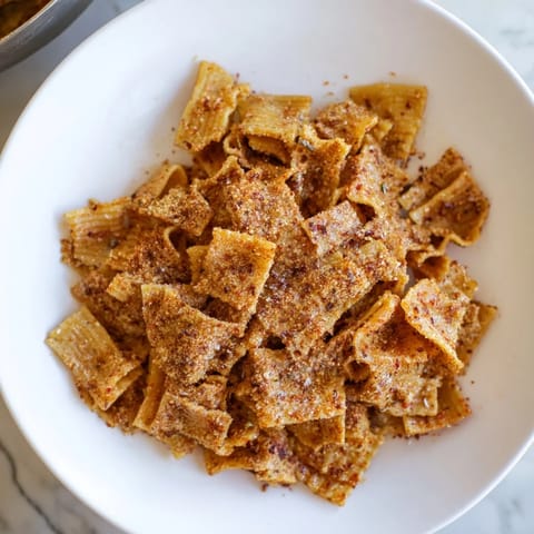 Golden baked pasta chips seasoned with garlic and paprika, ideal for gatherings.  