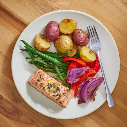 Freshly baked Lemon Herb Salmon & Potato, featuring flaky salmon with crispy potatoes and colorful roasted veggies.