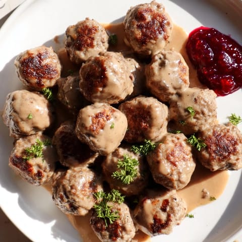 A close-up of a warm plate of comforting Swedish Meatballs, served with mashed potatoes.