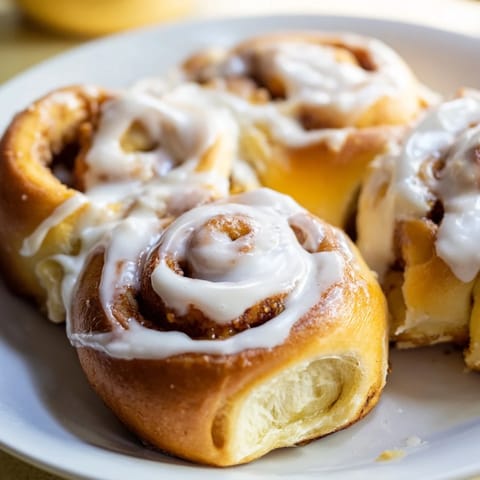 A close-up of golden-brown Pillow Soft Cinnamon Rolls, generously iced, perfect for brunch.