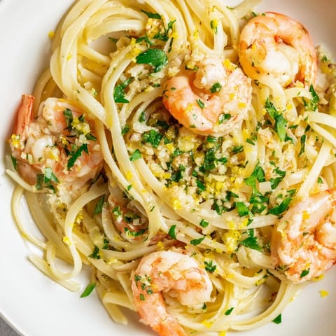 A skillet of bubbling Garlic Butter Shrimp Linguine beside a chilled glass of crisp white wine.