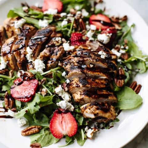 A vibrant platter of Honey Balsamic Chicken Salad featuring juicy chicken, sweet berries, and crumbled goat cheese.