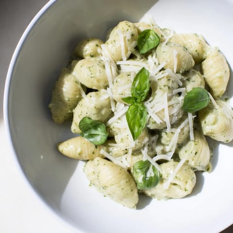 A close-up of Creamy Avocado Pesto Mac with tender pasta coated in vibrant green avocado-basil sauce and lemon zest.