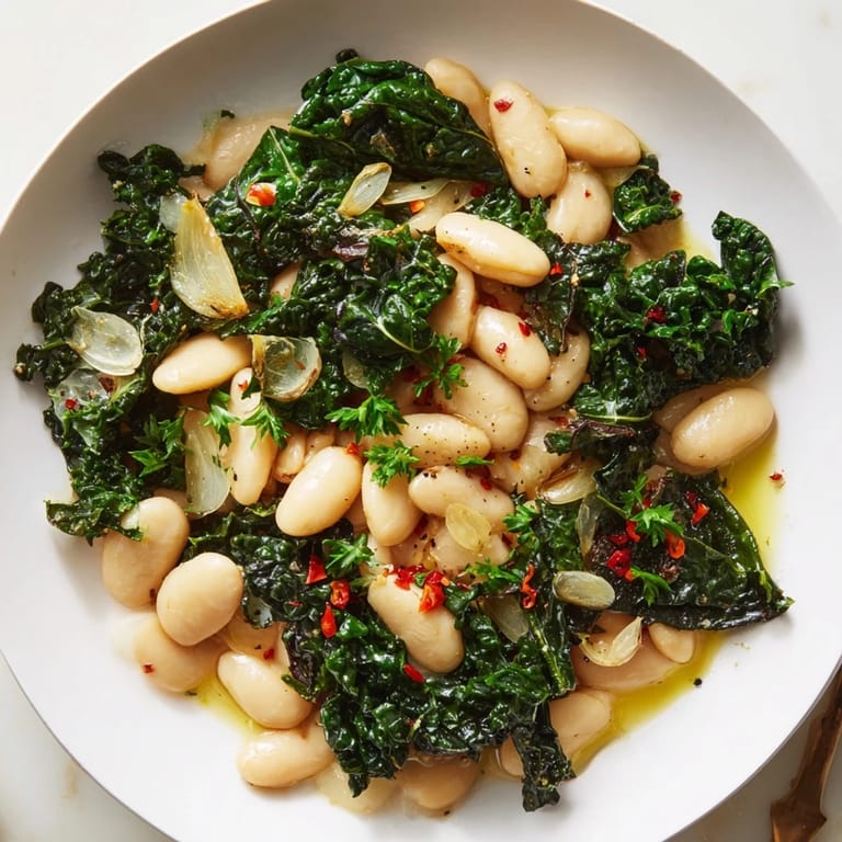 A rustic bowl of Garlicky Beans with Winter Greens, vibrant with fresh lemon and a drizzle of olive oil.