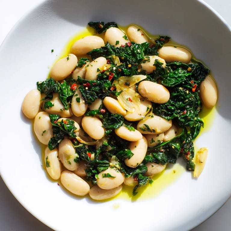 Close-up of a skillet filled with rich Garlicky Beans with Winter Greens, a delicious vegetarian comfort food.