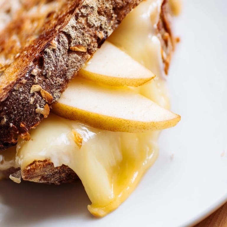 A close-up of a buttery, golden-brown Smoked Gouda & Apple Grilled Cheese with melted cheese and thin apple slices.